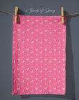 Bright pink floral tea towel with small daffodil motifs in pastel yellow and lilac, cheerful spring kitchen decor in a cottagecore style.