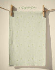 Sage green tea towel with tiny yellow daffodil repeat pattern, subtle pastel spring floral design for farmhouse and cottage kitchens