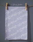 Lavender floral tea towel with delicate white blossom trails and subtle speckled texture, soft pastel cottagecore kitchen decor inspired by spring evenings.