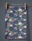 Navy blue floral tea towel with daffodils, blossom and wild garden flowers in soft pink, butter yellow and sage green, inspired by English cottage garden borders at dusk.