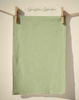 Soft sage green tea towel with delicate white ditsy floral sprig pattern inspired by English country gardens, pastel cottagecore spring kitchen decor