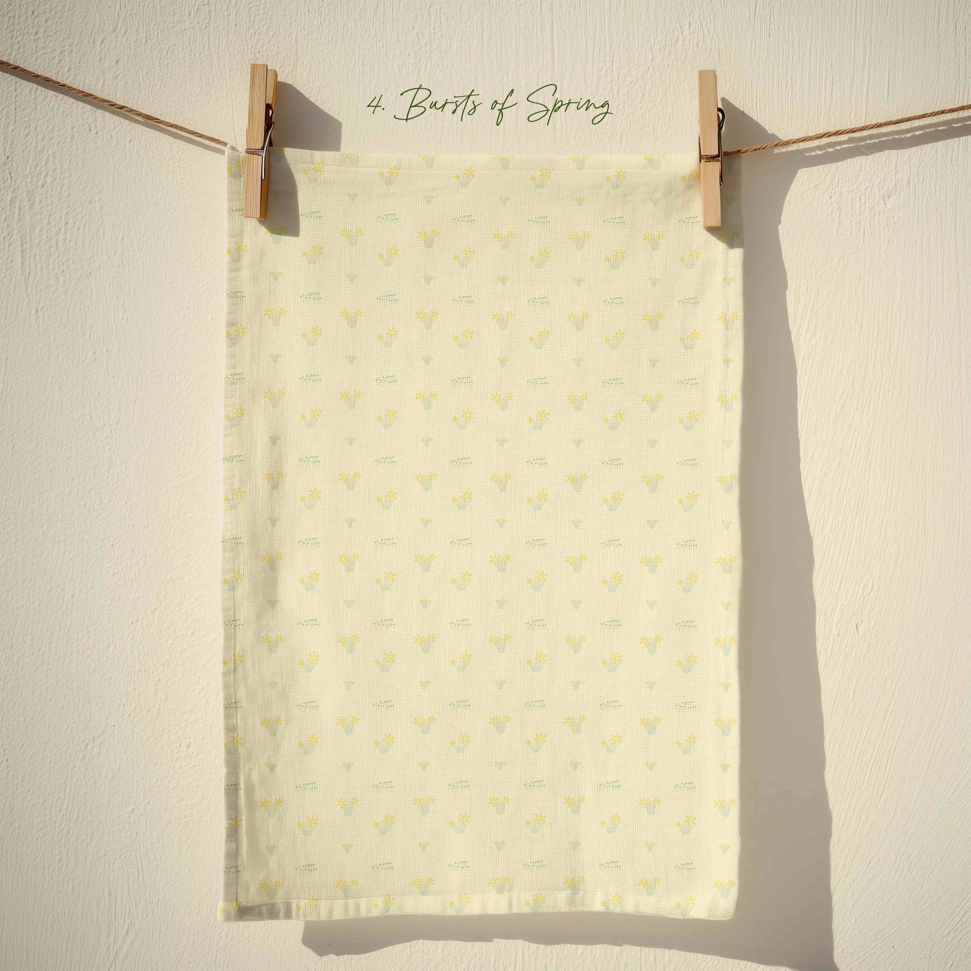 Pale cream spring tea towel with small scattered yellow floral motifs and subtle green accents in a delicate country cottage pattern