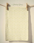 Pale cream spring tea towel with small scattered yellow floral motifs and subtle green accents in a delicate country cottage pattern