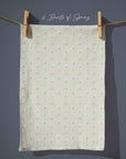 Soft sage green floral tea towel with small pastel daffodil motifs, gentle country garden pattern for spring cottage kitchens.