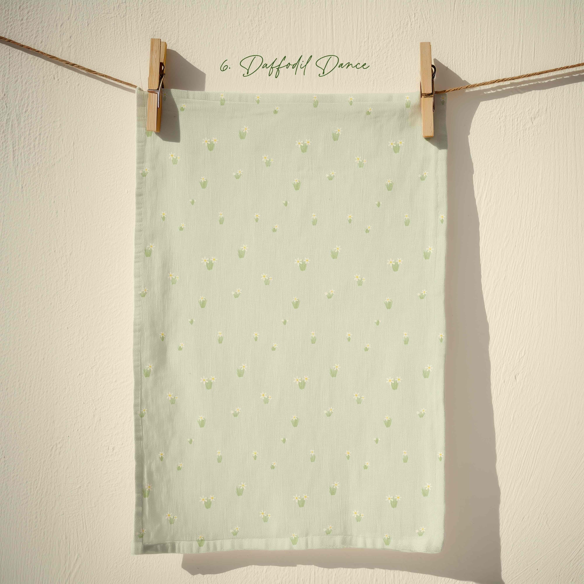 Sage green tea towel with tiny yellow daffodil repeat pattern, subtle pastel spring floral design for farmhouse and cottage kitchens