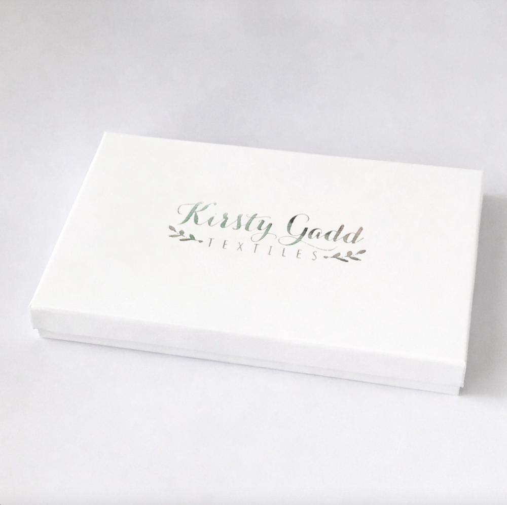 White presentation gift box with Kirsty Gadd Textiles branding in soft green lettering, elegant packaging for floral tea towel gift