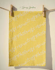 Bright yellow floral tea towel with flowing white blossom garlands in a bold spring country garden print, cheerful cottagecore kitchen decor