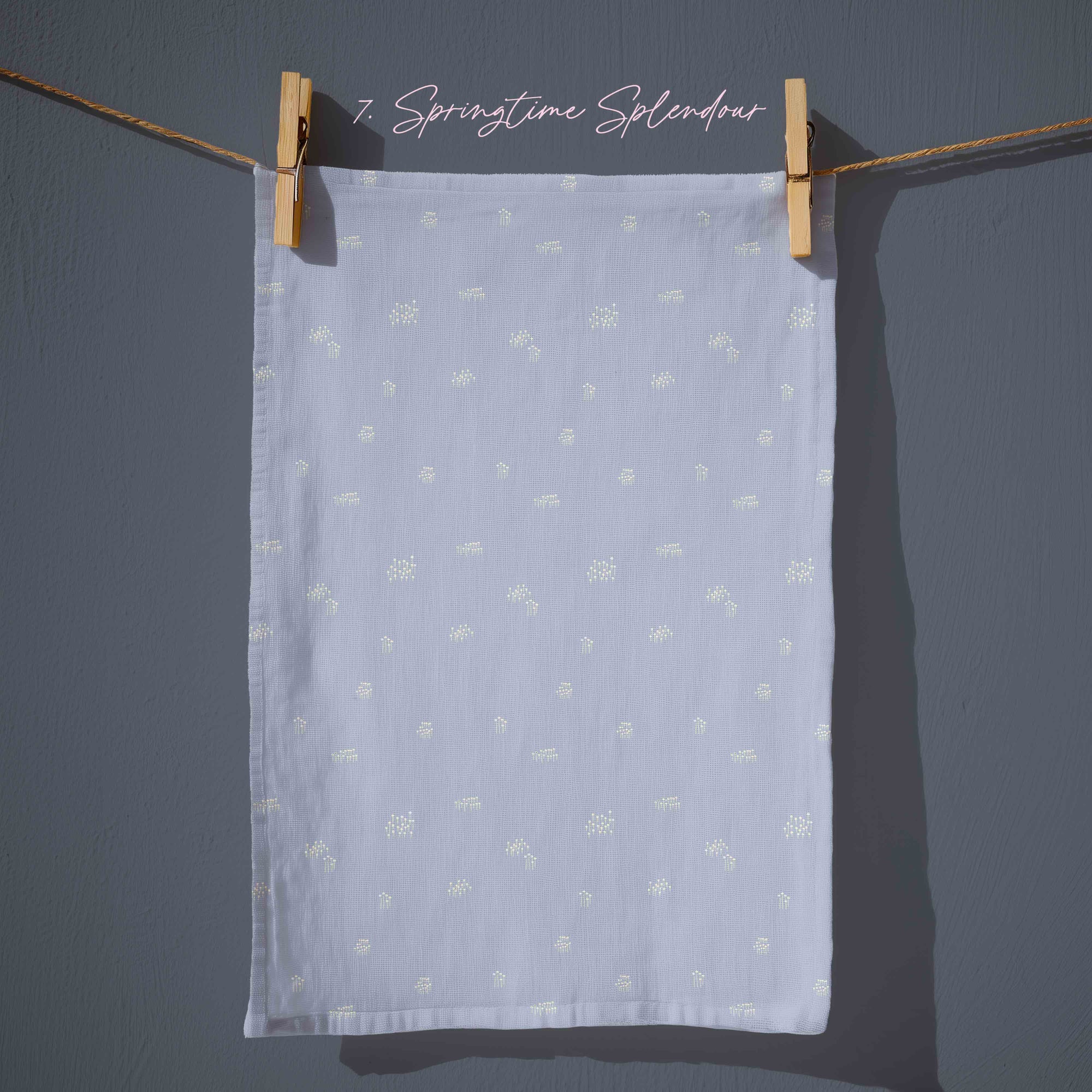Powder blue tea towel with tiny scattered white floral details, minimalist cottagecore kitchen textile inspired by early spring blooms.